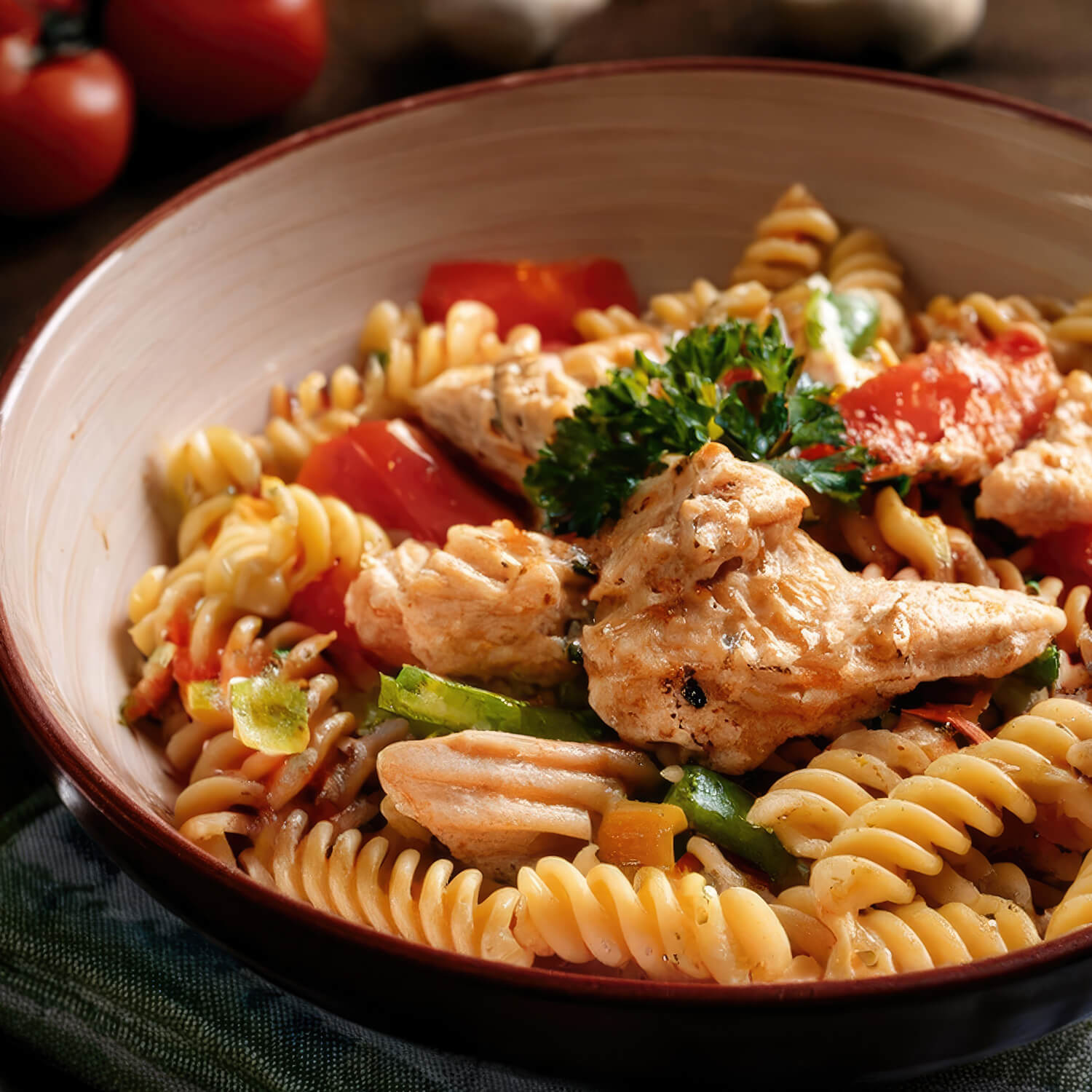 Ein Teller Fusilli-Pasta mit saftigem Hähnchen, frischen Tomaten und Kräutern, serviert auf einem rustikalen Tisch