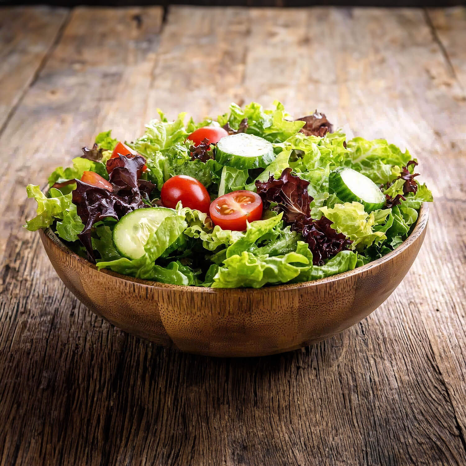 Holzschale mit gemischtem frischen Salat, garniert mit Tomaten und Gurken