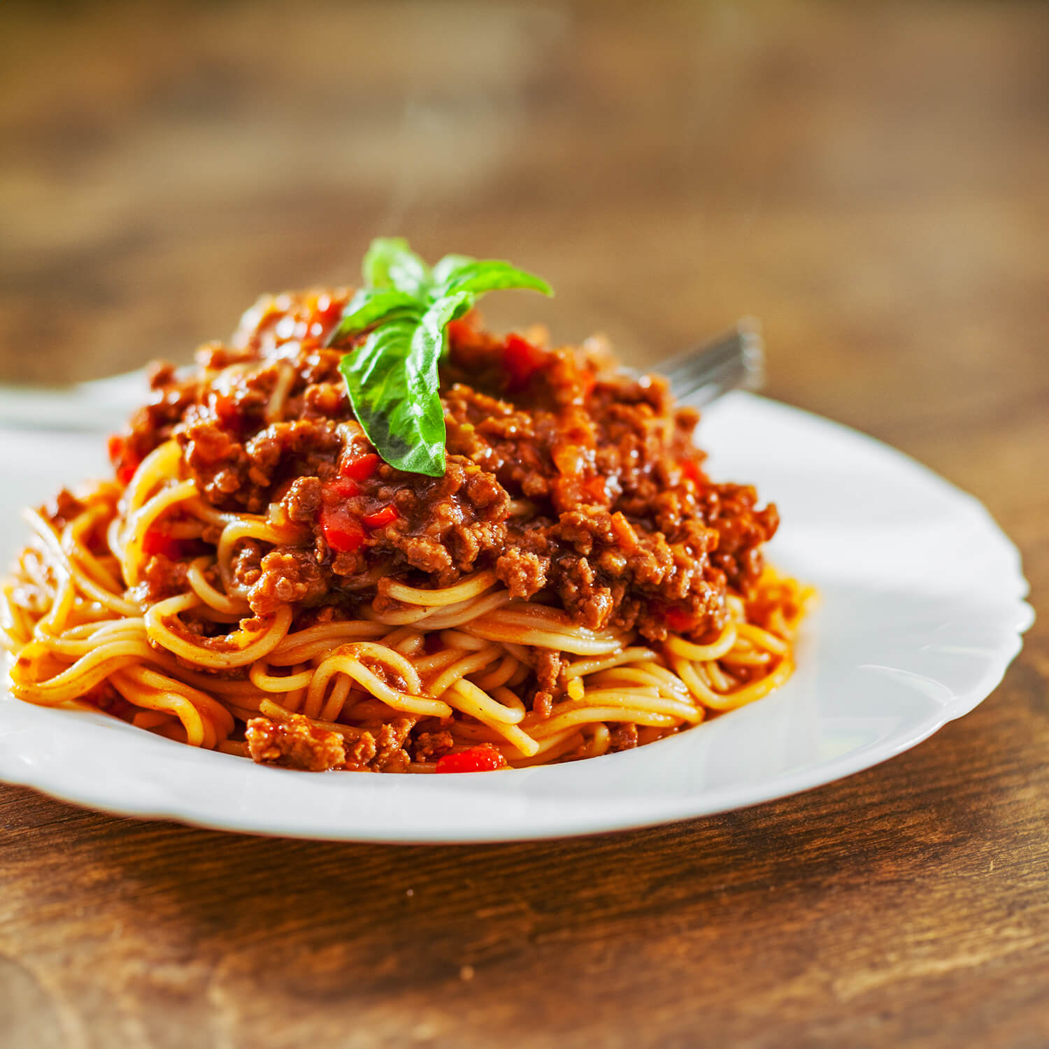 Teller mit Pasta Bolognese, verfeinert mit frischem Basilikum und Parmesan